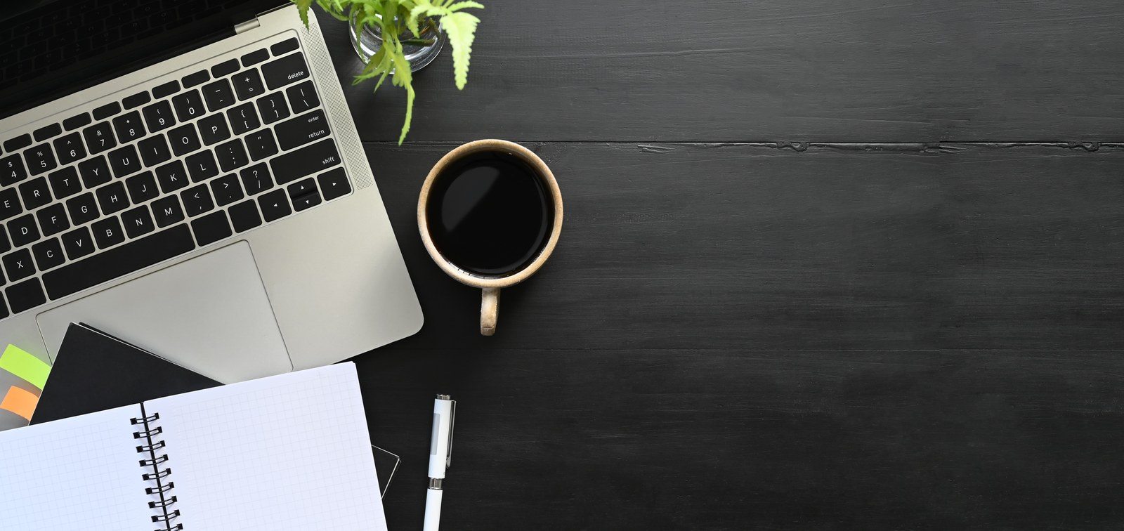 Mesa de trabalho com café, notebook e caderno